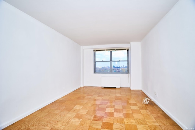 spare room featuring radiator and light parquet floors