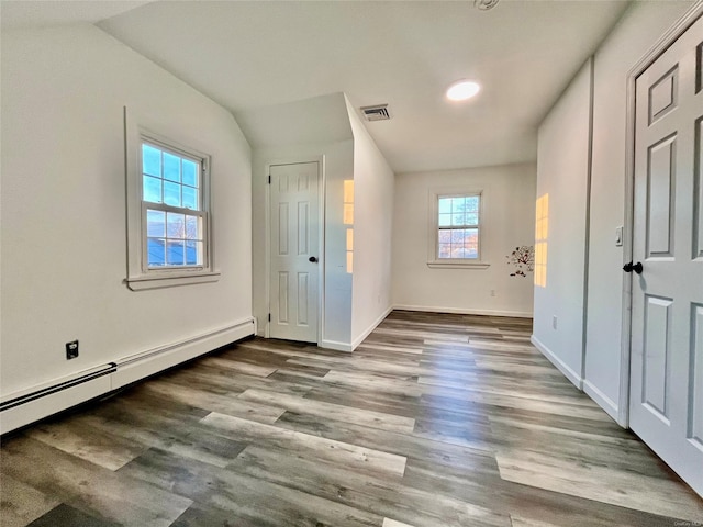 unfurnished bedroom with vaulted ceiling, light hardwood / wood-style flooring, and baseboard heating