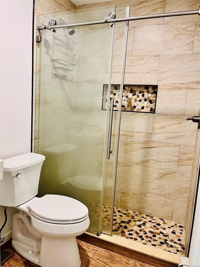 bathroom featuring hardwood / wood-style flooring, toilet, and a shower with shower door