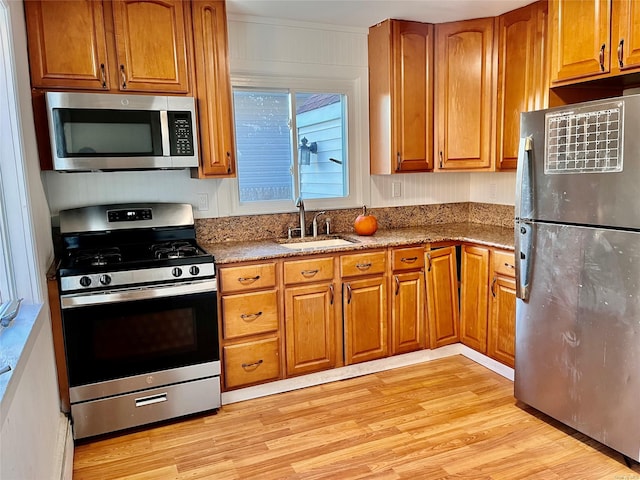 kitchen featuring stone counters, appliances with stainless steel finishes, light hardwood / wood-style flooring, and sink