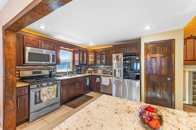 kitchen featuring appliances with stainless steel finishes, light stone counters, and sink