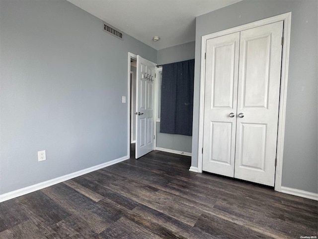 unfurnished bedroom with dark hardwood / wood-style flooring and a closet