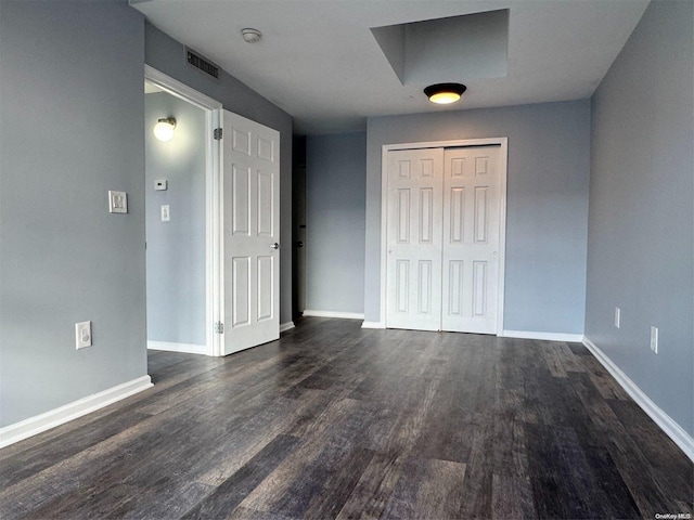 unfurnished bedroom with a closet and dark hardwood / wood-style floors