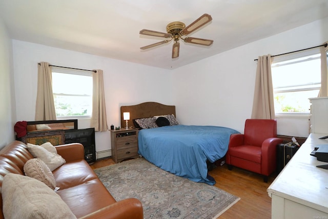 60 Tanglewood Dr, Smithtown, NY 11787 - bedroom with multiple windows, baseboard heating, light wood-style floors, and a ceiling fan