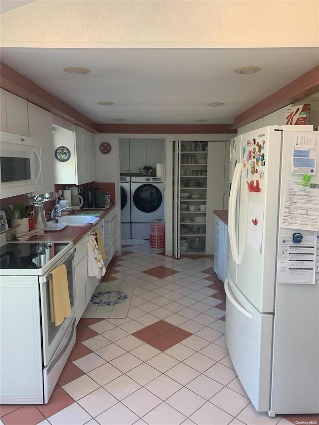kitchen with sink, white appliances, washing machine and dryer, and white cabinets