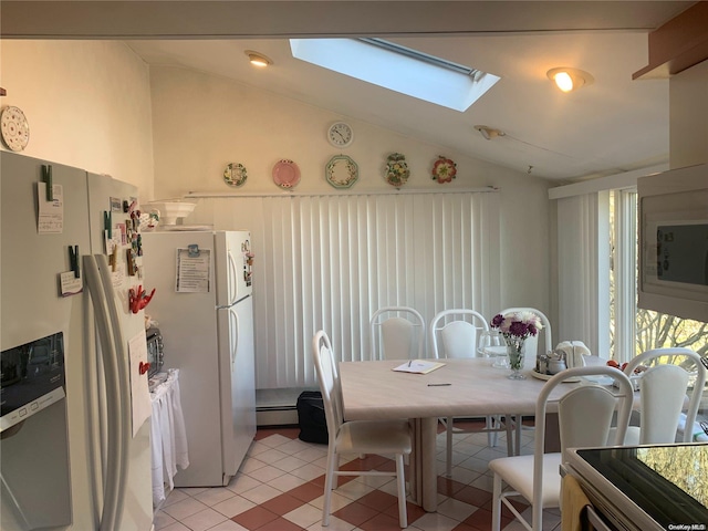 tiled dining area with a baseboard heating unit and vaulted ceiling with skylight