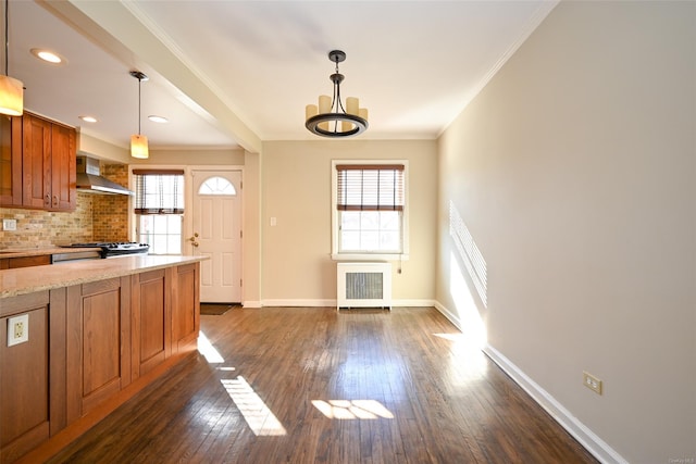 kitchen featuring crown molding, gas stove, radiator, wall chimney range hood, and decorative light fixtures