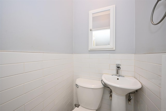 bathroom featuring tile walls and toilet