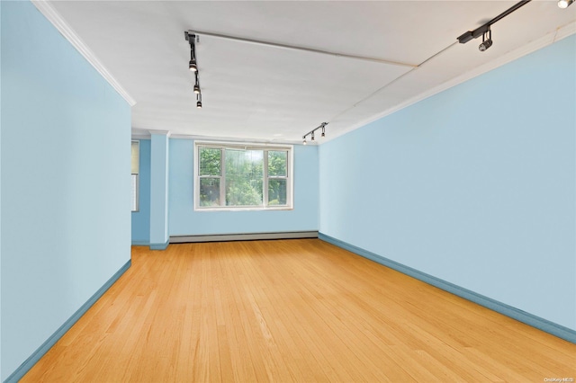 unfurnished room with track lighting, ornamental molding, baseboard heating, and light hardwood / wood-style flooring