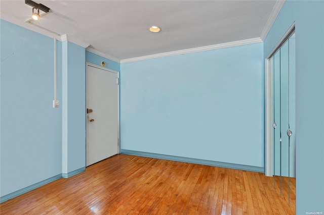 empty room with ornamental molding and light hardwood / wood-style flooring