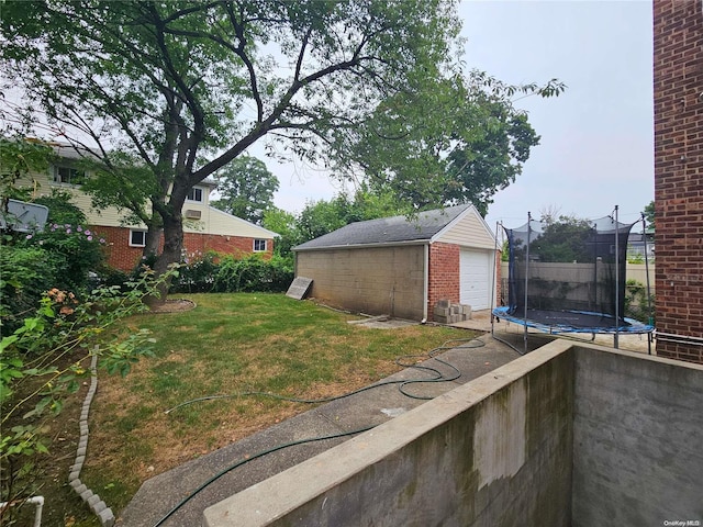 view of yard featuring a garage, a trampoline, and an outbuilding