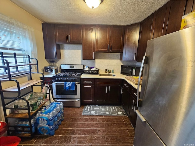 kitchen featuring a textured ceiling, stainless steel appliances, dark brown cabinetry, and sink