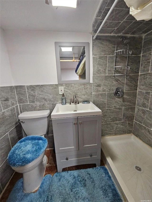 bathroom featuring tiled shower, vanity, tile walls, and toilet