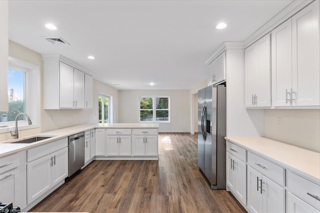 kitchen with white cabinets, sink, appliances with stainless steel finishes, dark hardwood / wood-style flooring, and kitchen peninsula