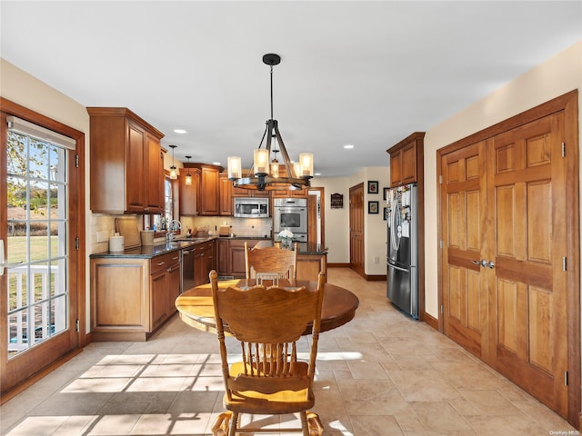 kitchen with a notable chandelier, baseboards, backsplash, dark countertops, and appliances with stainless steel finishes