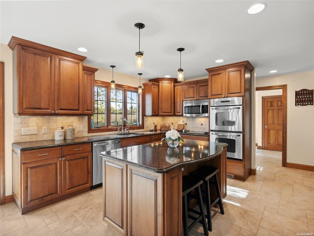 kitchen with a center island, a sink, decorative backsplash, brown cabinets, and stainless steel appliances
