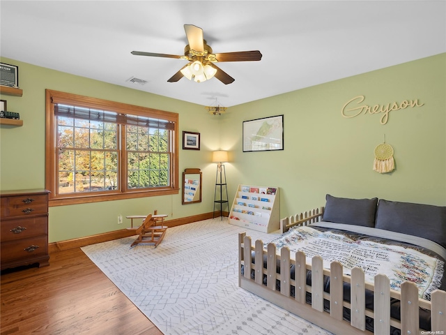 bedroom with baseboards, visible vents, a ceiling fan, and wood finished floors