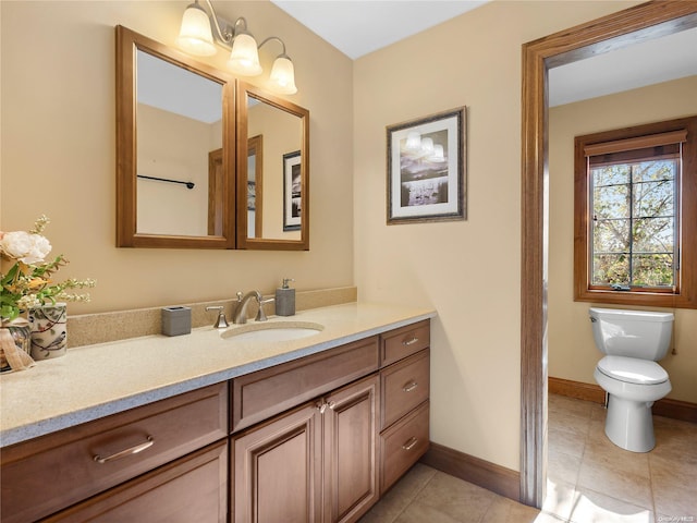 bathroom with toilet, baseboards, vanity, and tile patterned flooring