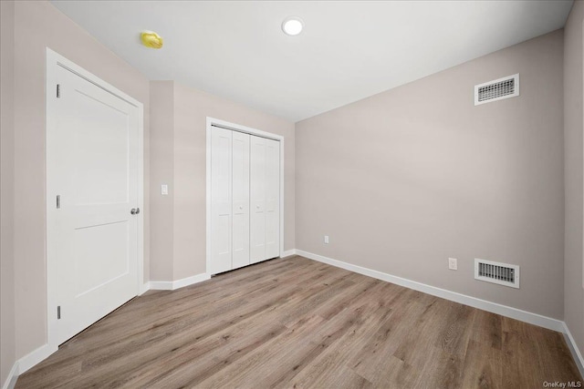 unfurnished bedroom with light wood-type flooring and a closet