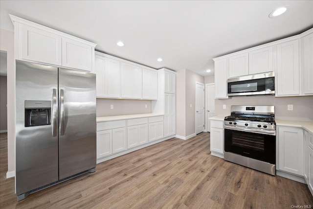 kitchen with stainless steel appliances, white cabinetry, and light wood-type flooring