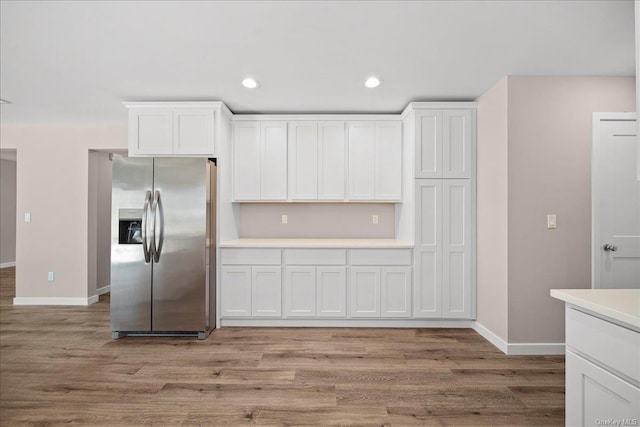 kitchen with stainless steel refrigerator with ice dispenser, white cabinets, and light hardwood / wood-style floors