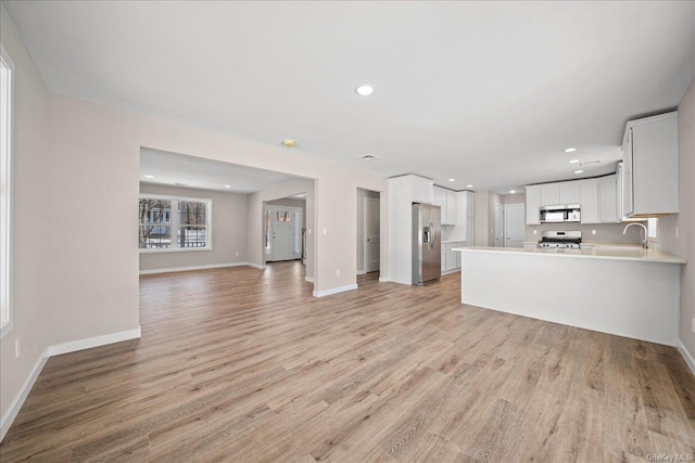 unfurnished living room with sink and light hardwood / wood-style flooring