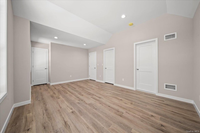 spare room featuring vaulted ceiling and light hardwood / wood-style flooring