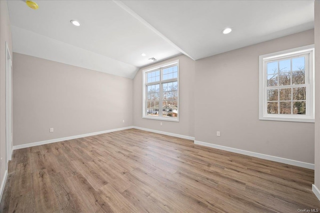 unfurnished room featuring lofted ceiling and light wood-type flooring