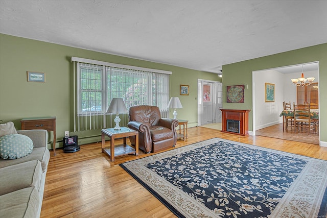 1519 Saint Louis Ave, Bay Shore, NY 11706 - living area with a chandelier, light wood-style floors, baseboard heating, a textured ceiling, and baseboards