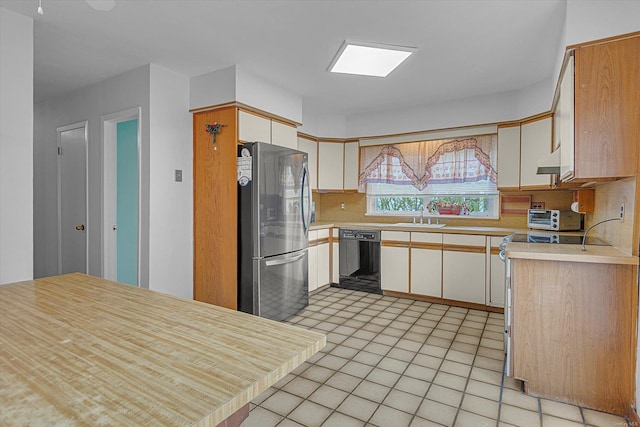 1519 Saint Louis Ave, Bay Shore, NY 11706 - kitchen featuring freestanding refrigerator, black dishwasher, decorative backsplash, a sink, and light countertops