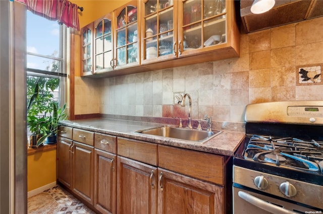 103 Cooper St, Brooklyn, NY 11207 - kitchen with stainless steel gas range oven, a sink, tasteful backsplash, brown cabinetry, and range hood
