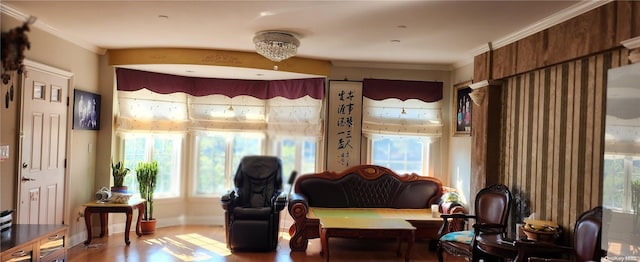 living area featuring plenty of natural light, wood-type flooring, and crown molding