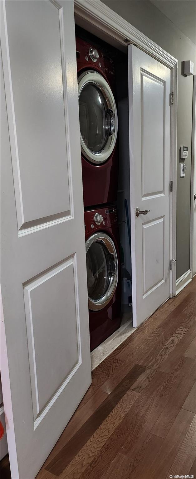 laundry room with dark hardwood / wood-style floors and stacked washing maching and dryer