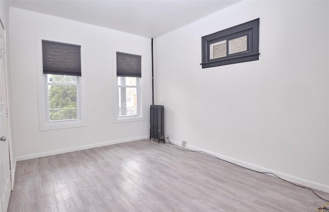 spare room with radiator, baseboards, and wood finished floors