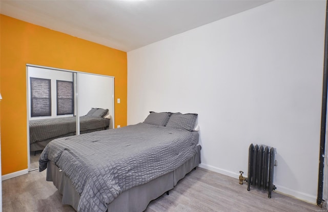 bedroom with radiator heating unit, baseboards, and wood finished floors