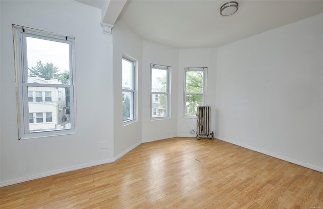 spare room with light wood-type flooring, baseboards, and radiator
