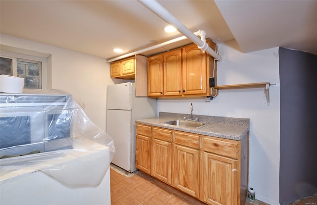 kitchen featuring light countertops, freestanding refrigerator, a sink, and recessed lighting
