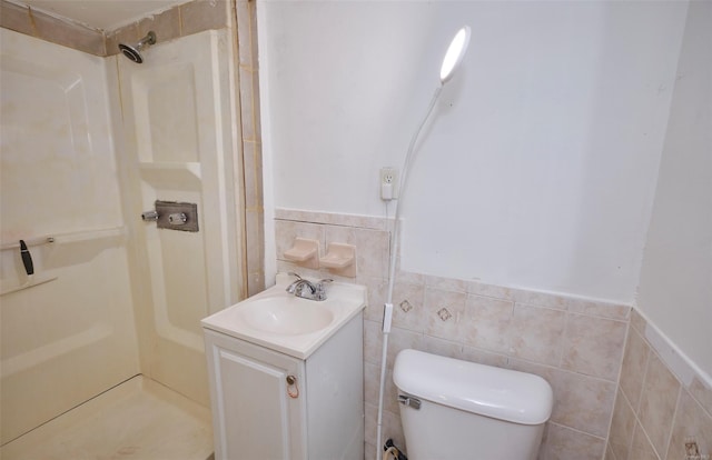 bathroom featuring toilet, wainscoting, tile walls, a stall shower, and vanity