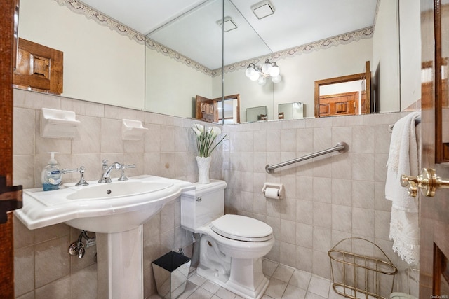 half bathroom with tile patterned floors, toilet, and tile walls