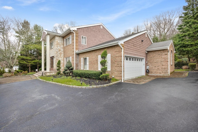 view of side of property featuring a garage, brick siding, and driveway