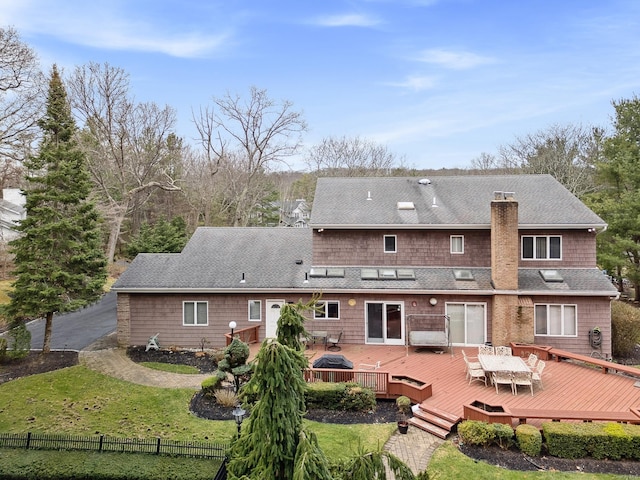 back of house featuring fence, a deck, a lawn, and a chimney