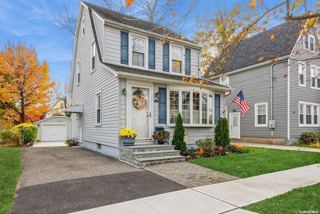 view of front of home featuring a front lawn, a garage, and an outbuilding