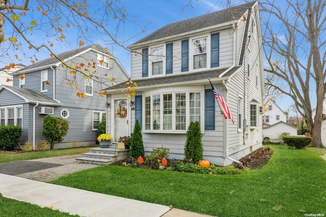 view of front of house featuring a front lawn and a wall unit AC