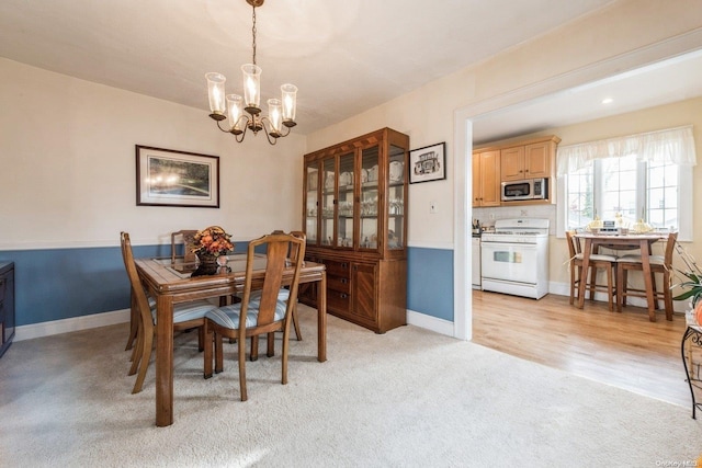 dining area with light carpet and a chandelier