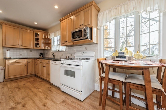 kitchen with light hardwood / wood-style floors, backsplash, white appliances, and sink