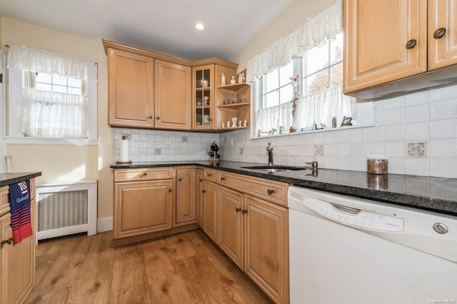 kitchen with hardwood / wood-style floors, dishwasher, a healthy amount of sunlight, dark stone countertops, and sink