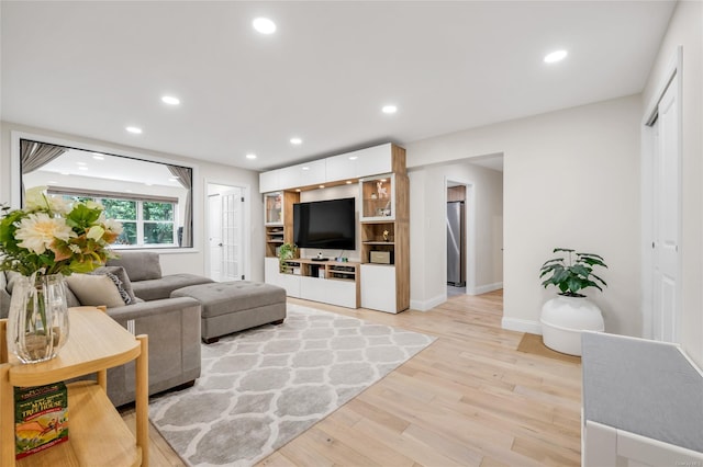 living room featuring baseboards, light wood-style flooring, and recessed lighting