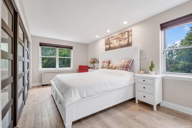 bedroom featuring multiple windows, light wood-style flooring, and baseboards