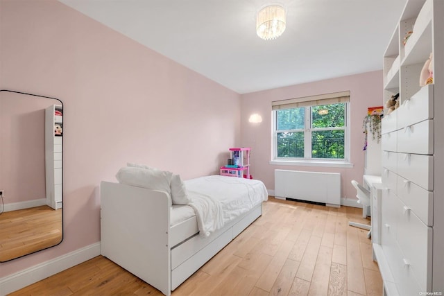 bedroom featuring radiator heating unit, light wood-type flooring, and baseboards