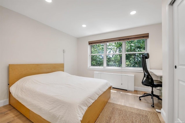 bedroom featuring radiator heating unit, baseboards, wood finished floors, and recessed lighting